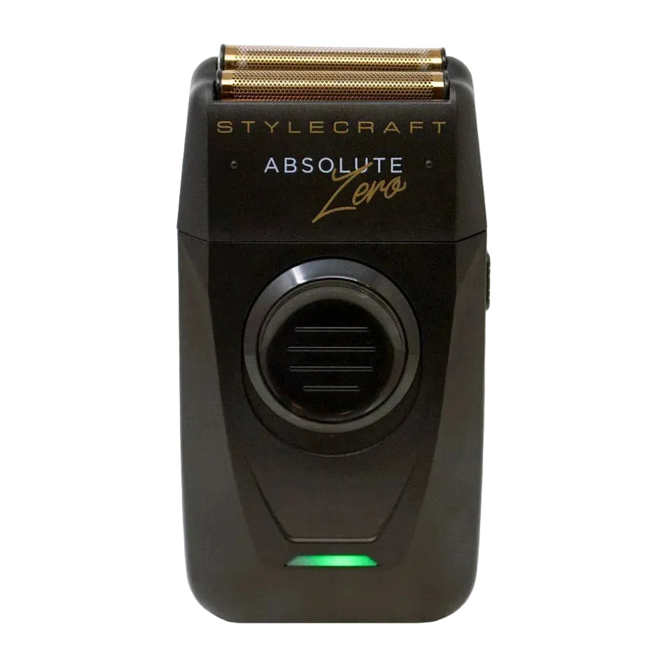 A black Stylecraft Absolute Zero electric shaver with a gold-toned triple-edge blade and a green indicator light, shown against a plain light gray background.