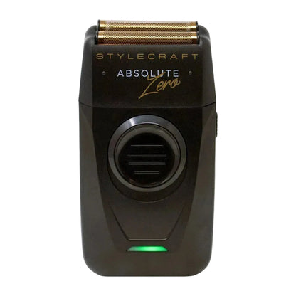 A black Stylecraft Absolute Zero electric shaver with a gold-toned triple-edge blade and a green indicator light, shown against a plain light gray background.