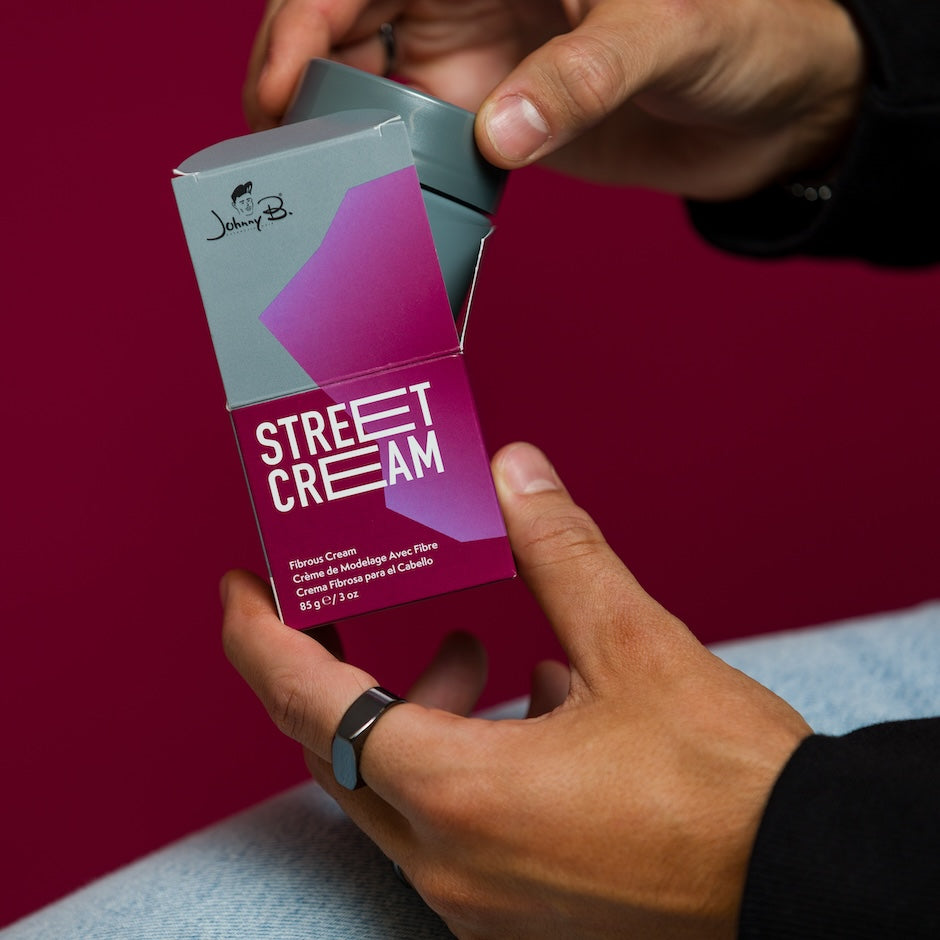 Person holding a 'Street Cream' product packaging against a red background